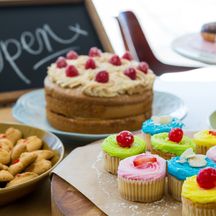 Close-up of various sweet foods on table with open signboard in cafete