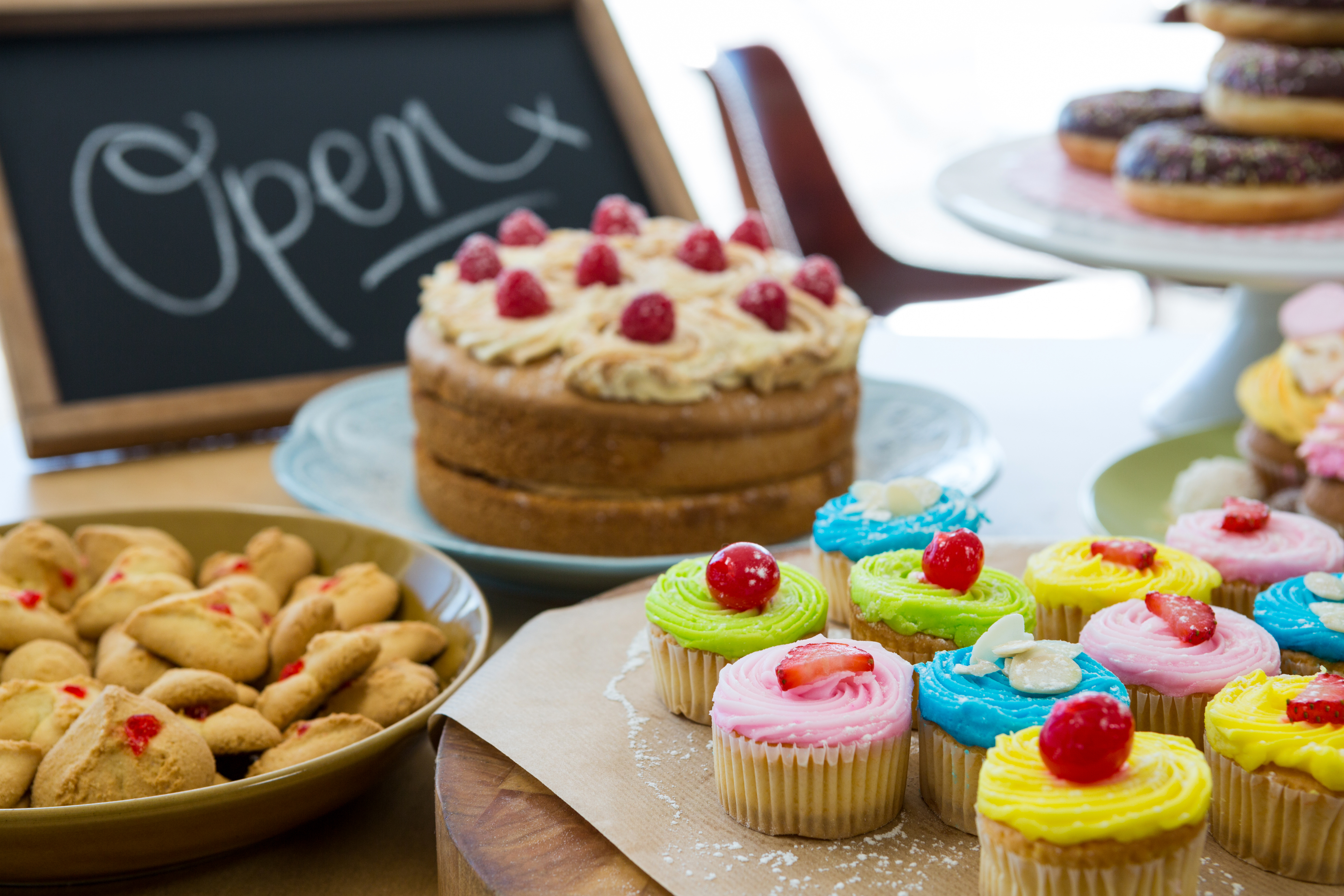 Close-up of various sweet foods on table with open signboard in cafete